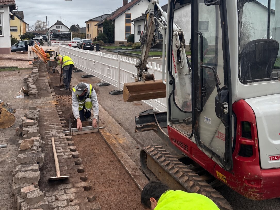 Operarios de COTELCO trabajando en la calzada junto a miniexcavadora durante la obra civil y canalización.