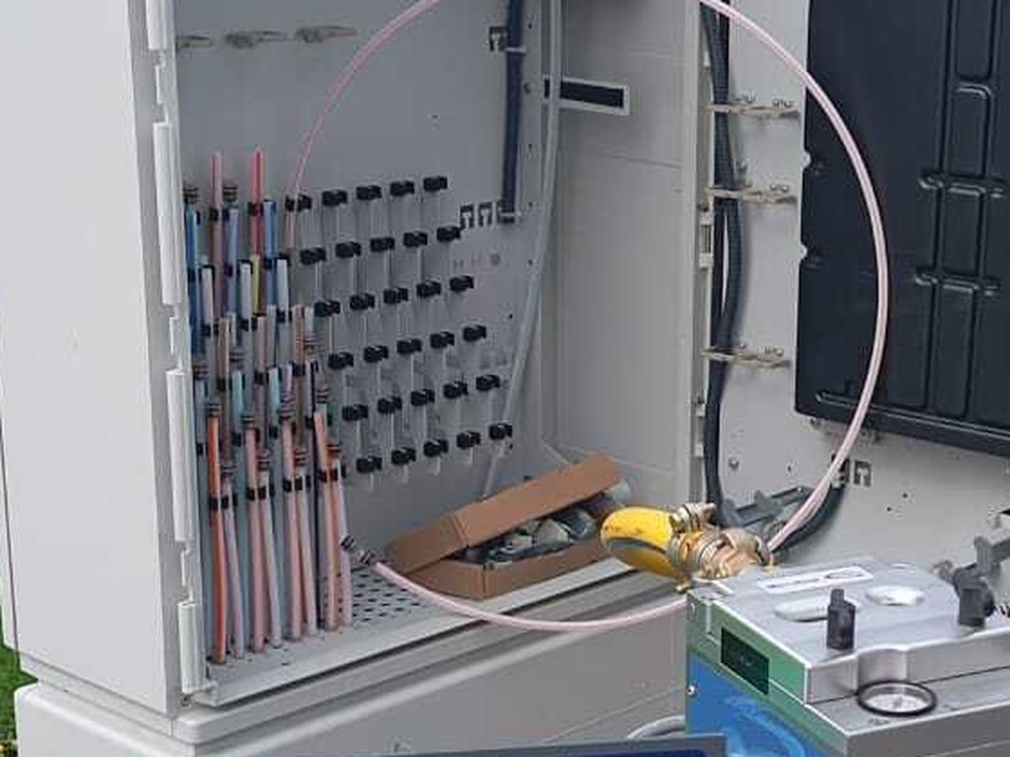 Detalle de tubos y cables de fibra óptica en armario con equipo de medición durante el despliegue FTTH.