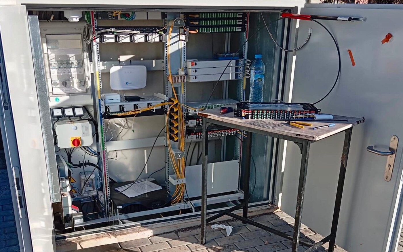Armario de fibra óptica con racks, bandejas de empalme y conexiones FTTH durante el despliegue en campo